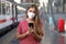 Young woman wearing KN95 FFP2 face mask waiting train at the station. Caucasian woman using smart phone in train station