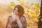 Young woman wearing knitted poncho having picnic in a forest: drinking tea and picking apples