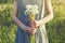 Young woman wearing linen dress holding bouquet of beautiful fresh dandelion flowers