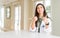 Young woman wearing medical coat at the clinic as therapist or doctor success sign doing positive gesture with hand, thumbs up