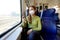 Young woman wearing medical mask relaxing in train seat while using smartphone app. Business woman enjoying view texting on mobile