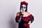 Young woman wearing mexican day of the dead makeup looking stressed and nervous with hands on mouth biting nails