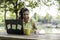 Young woman wearing open protective face mask using laptop outdoors - Female entrepreneur taking notes while calling with cell