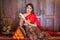 Young woman wearing a original traditional red Thai dress and golden ornaments sit on traditional bed and pillow holding a jasmine