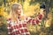 Young Woman wearing plaid shirt with retro photo camera taking selfie shot outdoor