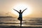 Young woman wearing protective surgical face doing yoga work out on the beach at sunset.