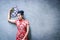 Young woman wearing red Chinese dress Welcome the new year Holding a blue fan The background is a plaster wall.