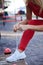 Young woman, wearing red fitness outfit, tying shoe laces on white sneakers. Process of fastening sport shoes. Close-up shot of