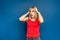 Young woman wearing red shirt standing over blue background with hand on head. Omg, shoked, surprised girl