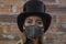 Young woman wearing sparkly black face mask against brick wall