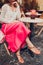 Young woman wearing stylish outfit with accessories in outdoor cafe. Close-up of female legs with shoes