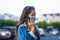 Young woman wearing surgical mask on street while using mobile phone. Portrait of young woman wearing a protective mask to prevent