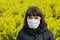 Young woman wearing a surgical protective mask on the background of rapeseed field