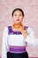 Young woman wearing traditional andean dress, facing camera doing sign language word for identification papers