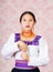 Young woman wearing traditional andean dress, facing camera doing sign language word for meter