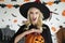 Young woman wearing vampire cloth holding a Halloween pumpkin and making a scary face