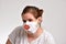 Young woman wearing a white cloth facemask for protection against coronavirus and holding a photo prop kissing mouth.