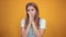 Young woman wearing white t-shirt, over orange background shows emotions