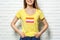 Young woman wearing yellow t-shirt with lesbian flag near white brick wall. LGBT concept