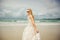 Young woman in wedding dress goes over sea turning back. bride on the beach.