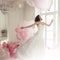 Young woman in wedding dress in luxury interior flies on pink and white balloons.