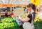 Young woman weighing bananas on electronic scales in produce department of the Auchan store