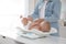 Young woman weighting her cute baby at home, closeup. Health care