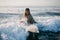 young woman in wetsuit with surfboard going into ocean