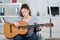 Young woman on wheelchair playing guitar