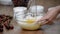 Young woman whipping dough in a bowl. Making cherry clafoutis