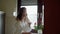 Young woman in white bathrobe drinks coffee or tea and sitting on the stone table in the cozy kitchen at the morning