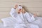 Young woman in white bed in bathrobe, eye mask, female yawns