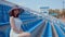 Young woman in white dress and elegant hat looks at camera, sitting on stadium bleachers alone. Lonely spectator at