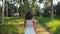 Young woman in white dress walking in jungle among palm trees on tropical island