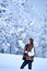 Young woman in white embroidered blouse and multicolored vest outdoors on sunny winter day.