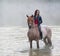 Young woman on a white horse stays in the water