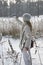 Young woman in a white jacket photographs a panorama of the coast of the winter forest lake on the phone