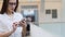 Young woman in a white shirt and glasses uses smartphone to search for information on the Internet.