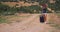 Young woman in white shorts goes alone along the path with luggage