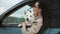 Young woman with white swiss shepherd dog is traveling by car and looking out the window. Travel lifestyle.
