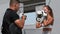 Young woman in white top having a boxing training outdoors with a male coach - punching the protectors on her coach's