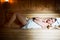 Young woman in white towel lying in Finnish sauna