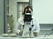 A young woman in a white uniform is working in a laboratory behind a microscope .