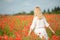 Young woman in white walking on a field of poppies