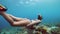 A young woman wih toned body snorekeling and swiming underwater near the corals.