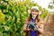 young woman winemaker with hat shows a heap of red grapes and looking at camera.