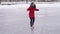 Young woman in winter clothes and high-heeled shoes glides on ice. Crazy female on outdoor ice rink in winter time.