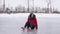 Young woman in winter clothes and high-heeled shoes sits on ice after fall. Crazy female crawling on outdoor ice rink in