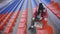 Young woman in winter clothes plays chess, sitting on stadium bleachers alone. Female in black cap with chess on sports