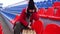 Young woman in winter clothes plays chess, sitting on stadium bleachers alone. Female in black cap with chess on sports